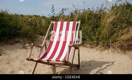Rot-weiß gestreifter Liegestuhl an einem Sandstrand Stockfoto