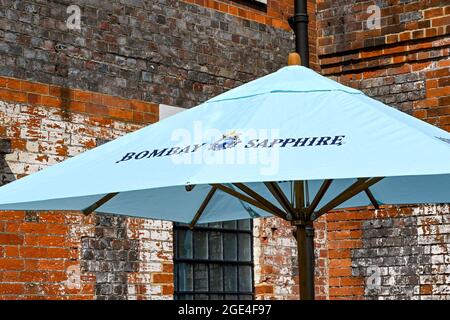 Whitchurch, Hampshire, England - August 2021: Sonnenschirm vor einem der alten Gebäude, die Teil der Bombay Sapphire Gin Distillery sind Stockfoto