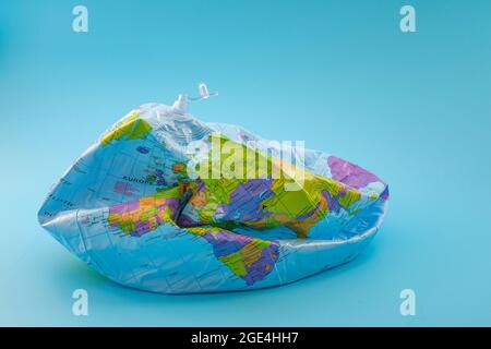 Konzept für globale Erwärmung, Klimakatastrophe und Umweltprobleme mit deflationiertem Globus auf blauem Hintergrund isoliert Stockfoto