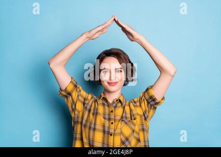 Foto von fröhlich sichere Dame heben Hände zeigen Dach Figur tragen karierte Hemd isoliert blauen Hintergrund Stockfoto