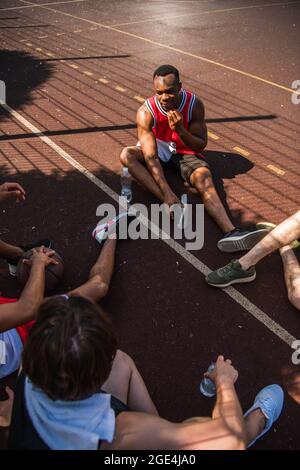 Blick von oben auf den afroamerikanischen Sportler, der mit Freunden mit einem Basketballball auf dem Spielplatz spricht Stockfoto