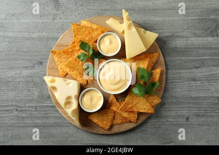 Tafel mit Käsesauce, Chips, Käse und Petersilie auf grauem Tisch Stockfoto