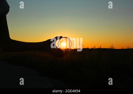 Polarizing filter in hand on sunset background. Stockfoto