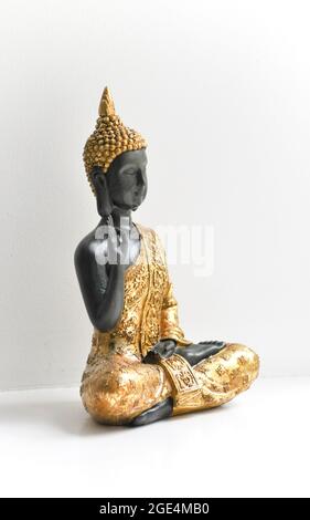 Eine goldene Buddha-Statue, die in der Mitte des Bildes vor einem weißen Hintergrund aufgestellt ist. Stockfoto