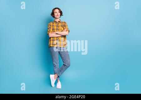 Foto von pensive Dame gekreuzte Arme suchen leeren Raum tragen kariertes Hemd Jeans Schuhe isoliert blaue Farbe Hintergrund Stockfoto