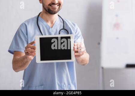 Teilansicht eines lächelnden Arztes, der ein digitales Tablet mit leerem Bildschirm zeigt Stockfoto