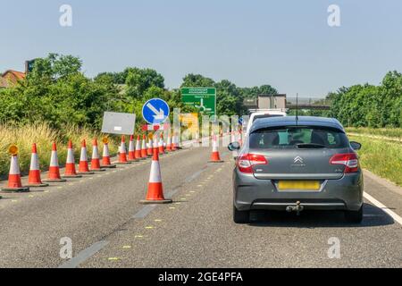 Autos, die auf der zweispurigen A17-Straße außerhalb von Sleaford in Lincolnshire durch einen abgesperrten Abschnitt von Straßenarbeiten Schlange stehen. Verkehr in Richtung Westen. Stockfoto