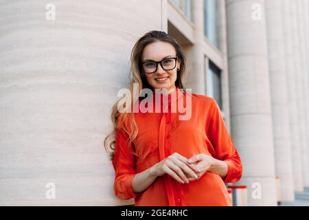 Junge Frau mit Brille neben dem modernen Gebäude. Stockfoto