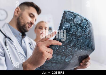 Verschwommener Arzt und Patient, der im Krankenhaus eine MRT-Untersuchung des Gehirns ansieht Stockfoto