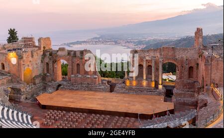 Sonnenuntergang auf dem antiken römisch-griechischen Amphitheater mit der Giardini Naxos Bucht im Hintergrund in Taormina, Sizilien, Italien Stockfoto