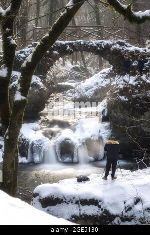 Schiessentuempel mit Fotograf im Mullerthal-Wald zur Winterzeit in Luxemburg Stockfoto