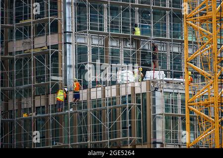 Bukarest, Rumänien - 12. August 2021: Bauarbeiter arbeiten an der Fassade eines neu erbauten Bürogebäudes in Bukarest. Stockfoto