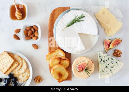 Käseplatte mit einer Auswahl von A Käse, Cracker, Feigen, Nüssen und Honig. Szene über dem Tisch auf einem hellen Hintergrund. Stockfoto