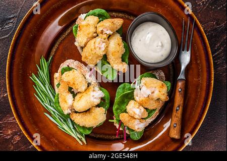 Sandwiches mit gebratenen Garnelen, Garnelen, Spinat und Mangold-Salat auf einem rustikalen Teller. Dunkler Hintergrund. Draufsicht Stockfoto