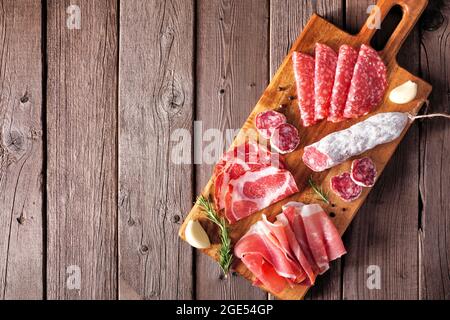 Italienische Antipasto-Fleischplatte mit Wurst, Prosciutto, Schinken und Salami. Draufsicht auf einem Servierbrett vor einem Holzhintergrund. Stockfoto