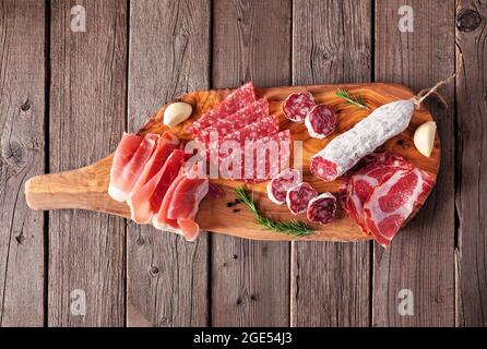 Fleischplatte mit Wurst, Prosciutto, Schinken und Salami. Draufsicht auf einem Servierbrett vor einem Holzhintergrund. Stockfoto