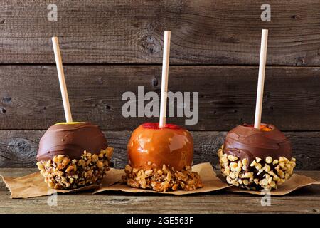 Drei Sorten herber Zuckeräpfel mit Schokolade und Karamell, Seitenansicht vor dunklem Holz-Hintergrund Stockfoto