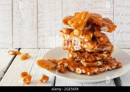 Stapel von traditionellen Erdnuss brüchigen Süßigkeiten Stücke vor einem weißen Holz Hintergrund Stockfoto