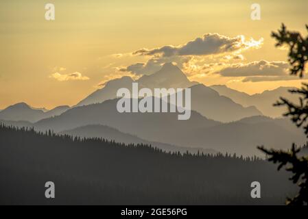 Goldener Himmel bei Sonnenuntergang und zurücktretende bewaldete Bergrücken mit Blick auf den Mount Hozomeen des Staates Washington vom Manning Park, BC, Kanada Stockfoto