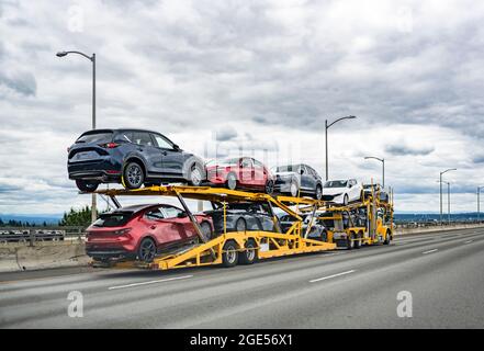 Professionelle leistungsstarke gelbe Big Rig industriellen Auto Spedition semi-Truck mit zwei Ebenen modularen hydraulischen Sattelauflieger Transport von Autos auf dem wi Stockfoto