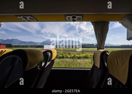 Bild eines leeren Bussitzes, aufgenommen während einer Fahrt in einem Fernbus auf einem Intercity-Service mit Fenstern, die die julischen alpen in slowenien zeigen Stockfoto