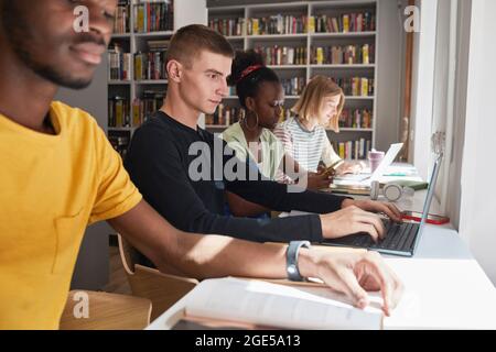 Seitenansicht auf verschiedene Gruppe von Studenten sitzen in Reihe während des Studiums in der Schulbibliothek, Platz kopieren Stockfoto