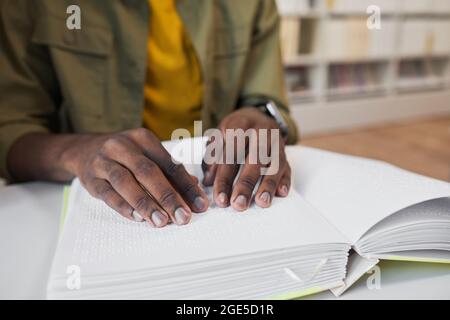 Nahaufnahme eines nicht erkennbaren afroamerikanischen Mannes, der in der Universitätsbibliothek Brailleschrift liest, Kopierraum Stockfoto