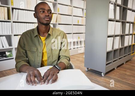 Porträt eines jungen afroamerikanischen Mannes, der in der College-Bibliothek Braille-Bücher liest, Kopierraum Stockfoto