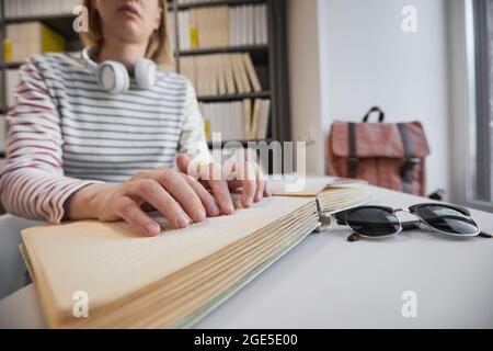 Nahaufnahme einer jungen blinden Frau, die in der Universitätsbibliothek Brailleschrift liest, Kopierraum Stockfoto