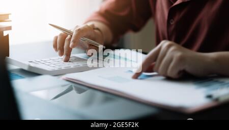 Junge Business Frau arbeitet am Schreibtisch mit einem Rechner, um die Zahlen zu berechnen, Finanz-Rechnungswesen Konzept. Arbeit von zu Hause Konzept Stockfoto