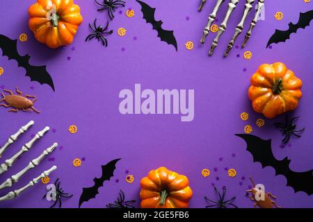 Happy Halloween Feiertagskonzept. Halloween-Dekorationen, Skelett Hände, Fledermäuse, Kürbisse auf lila Hintergrund. Halloween Party Grußkarte Mockup mit Stockfoto