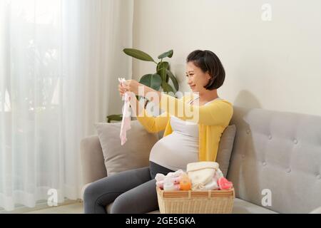 Frau, die Babykleidung im Wohnzimmer packt Stockfoto