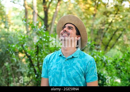 Lächelnder Mann mit Strohhut und blauem Polhemd in der Natur. Stockfoto