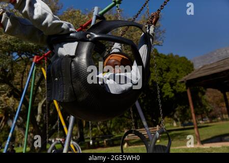 Schöne schwarze afrikanische Mädchen auf Schaukeln im Park Stockfoto