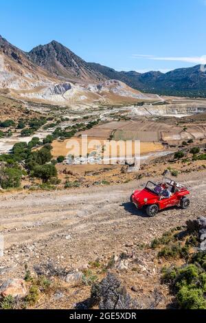 Touristen erkunden Nysiros mit einem roten Auto auf einer Schotterstraße, Vulkankaldera mit Bimssteinfeldern, gelben Schwefelsteinen, Stefanos und Alexandros Stockfoto