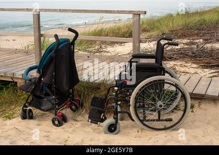 Rollstuhl und Kinderwagen auf Rampe am Strand aus der Nähe. Stockfoto