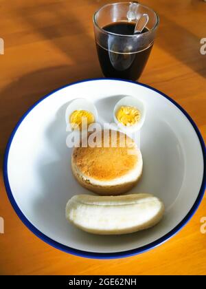 Hausgemachte Speisen auf weißem runden Teller auf Holztisch serviert. Tasse Kaffee auf die Seite des Teller legen. In den Teller haben die hart gekochten Eier, den Kuchen geschnitten Stockfoto