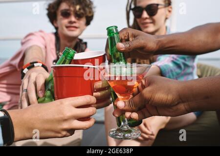 Hände von Freunden toasten mit Bierflaschen, Plastikbechern und martini-Gläsern auf der Party Stockfoto