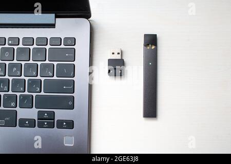 MOSKAU - 26. Juni 2020: Juul e-Zigarette Nikotindampfstab und Laptop mit usb-Ladegerät. Stockfoto