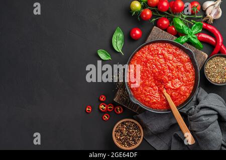 Italienische Tomatensauce, Pasta-Dressing, Pizza in einer Pfanne auf schwarzem Hintergrund. Stockfoto