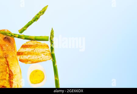 Frisch gegrilltes Brot, Spargel und Ei. Zum Frühstück gibt es Inridients. Gleichgewichtsschwimmende Lebensmittel. Balance Levitation Food. Vertikales Foto. Stockfoto