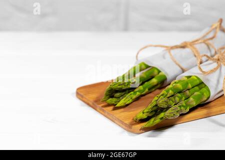 Frischer grüner Spargel auf Holztisch auf weißem Hintergrund. Gesunde pflanzliche Ernährung. Vegetarismus. Gemüsetapete. Kopieren Sie die Spase. Stockfoto