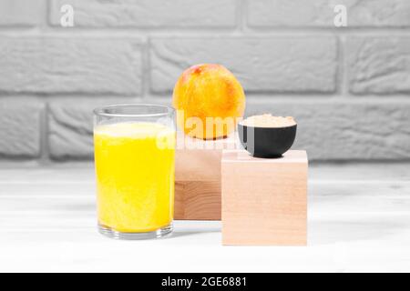 Kreatives Stillleben mit Frucht-Smoothie, Pfirsich und Maca auf Holzpodien auf weißem Backstein-Hintergrund, horizontal, Copy Space, Trendy Food Stockfoto