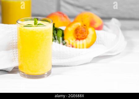 Smoothie mit Pfirsich und Minzblatt mit Stück Tuch auf weißem Backstein Hintergrund, horizontale Auflösung, gesunde Sommerdiät Stockfoto