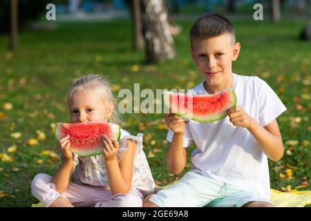 Zu niedlichen Kindern lttle Junge und Mädchen essen saftige Wassermelone im Picknick auf Herbst Parkwiese. Stockfoto