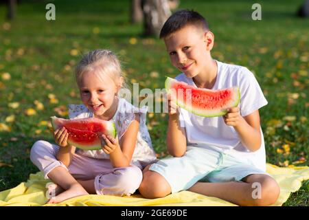 Zu niedlichen Kindern lttle Junge und Mädchen essen saftige Wassermelone im Picknick auf Herbst Parkwiese. Stockfoto