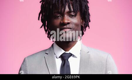 Porträt eines lächelnden afroamerikanischen Geschäftsmannes, isoliert auf Rosa Stockfoto