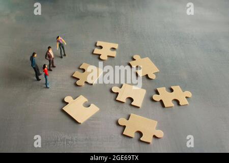Business Teamwork mit Scramble Puzzle Cooperation Unity Support Concept. Miniaturmenschen betrachten das Rätsel. Stockfoto