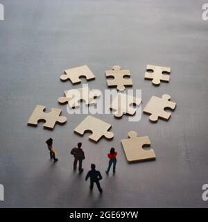 Business Teamwork mit Scramble Puzzle Cooperation Unity Support Concept. Miniaturmenschen betrachten das Rätsel. Stockfoto