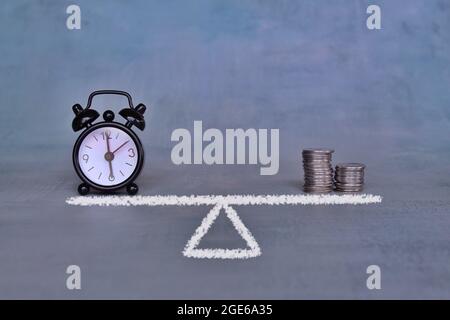Balance zwischen Zeit- und Geldkonzept. Wecker und Münzen auf Waage stapeln Stockfoto